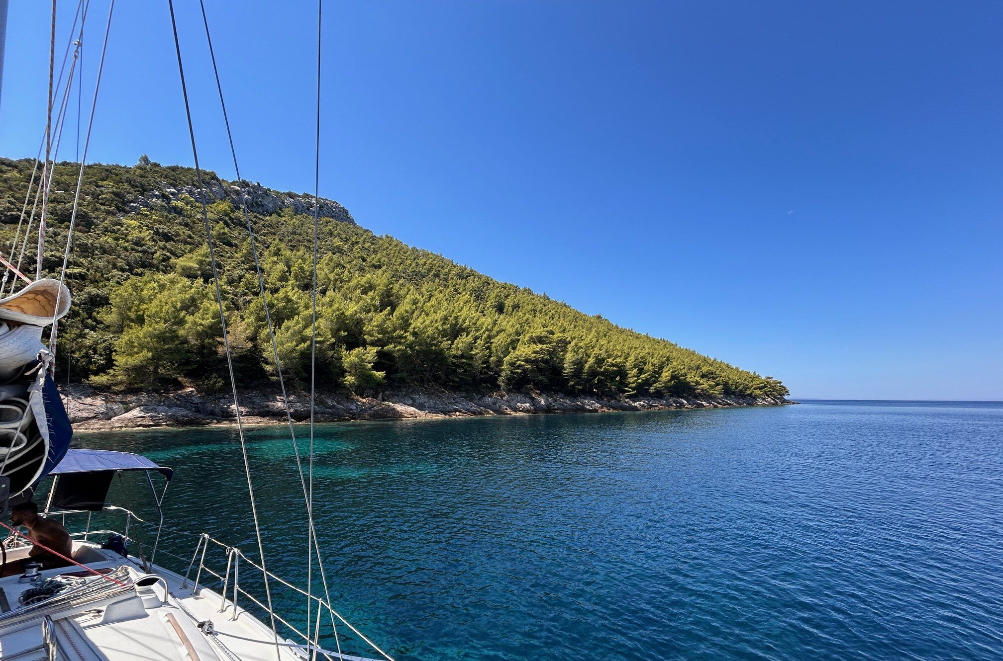 View from the deck of a sailing boat towards a wooded island