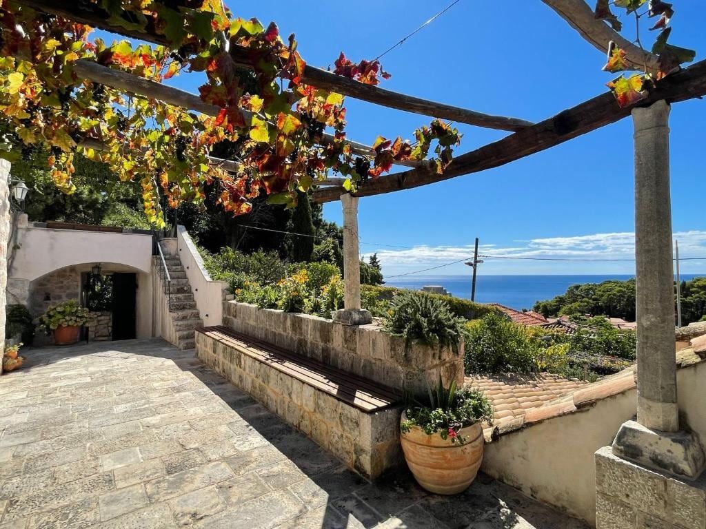Stone terrace under a vine pergola at Villa Anica Dubrovnik, with a view of the sea